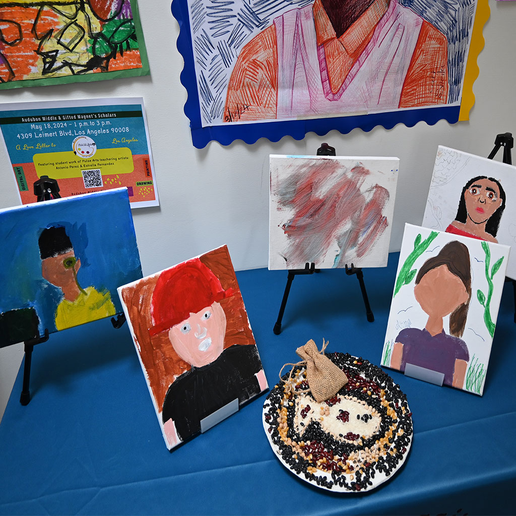 Self portrait on canvas display on the Pulse Arts table from Teacher Kemker classroom, teaching artist Estrella Fernandez.